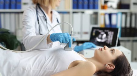 El médico sostiene la sonda de ultrasonido en el pecho del paciente en el primer plano de la clínica. Examen médico de mama en la clínica