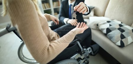Foto de Agent hands over keys to accommodation of persons in wheelchair. Getting social housing concept - Imagen libre de derechos