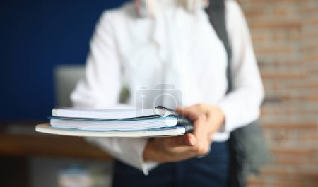 Téléchargez les photos : Female student holds folder and notebook in hands for studying. Girl is taking exams at university - en image libre de droit