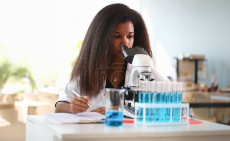 Téléchargez les photos : Femme noire scientifique étudiante chimiste dans les lunettes de protection mènent des recherches en utilisant le microscope pour la contamination bactérienne de l'eau pour rechercher un vaccin pour traiter les maladies en médecine
. - en image libre de droit