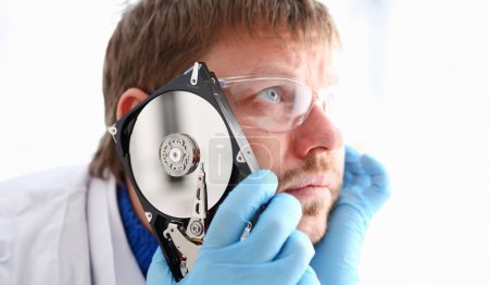 Photo for Repairman attached the hard drive of the computer to his ear. Listens to knock and crack reveals the problematic problems and ringing affecting correct operation of hard drive, tests and repairs. - Royalty Free Image