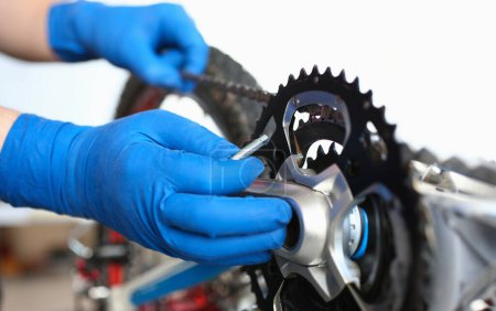Gloved hands guy repair mechanical part bicycle. Self-tuning bike during self-isolation. Diagnostics and assembly. Repair work at home. Adjustment bicycle mechanism. Bicycle service