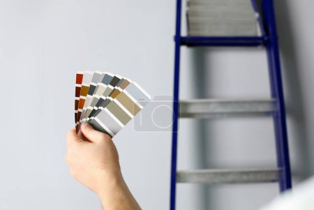 The designer holds pantone fan of color guide in hand. Selection of colors for the color of the walls apartment distribution during promotion concept