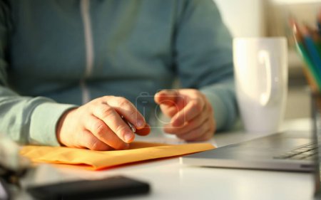 männliche Hand mit silbernem Stift. Adresse auf gelbem Briefumschlag für Bewerbungskonzept ausfüllen