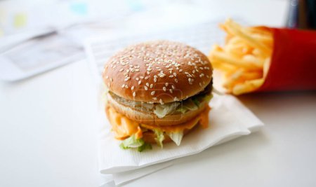 Hamburguesa y papas fritas con auriculares yacen en el escritorio en la oficina durante la pausa para el almuerzo concepto de entrega de alimentos
