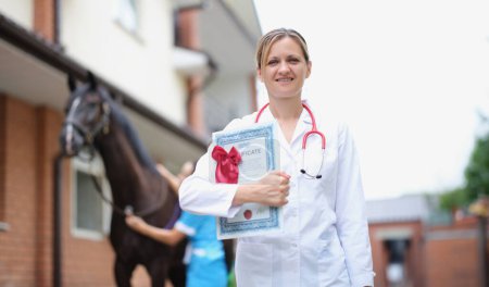 Beautiful woman veterinarian is holding medical certificate next to horse. Fundamentals of anti-doping control in equestrian sports