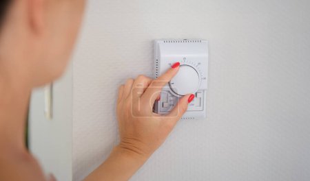 Hand stellt Taste der Steuereinheit der Heizung und Kühlung des Hauses Nahaufnahme ein. Klimaanlage für Haus oder Büro