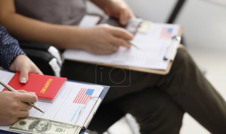Personas sentadas en línea con los documentos para obtener la visa americana y el primer plano de dinero. Viaje a EE.UU. asistencia con el concepto de papeleo