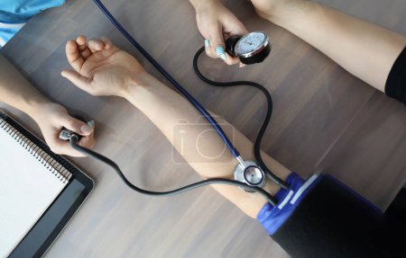 Foto de Médico midiendo la presión arterial con tonómetro en la mesa en el primer plano de la clínica. Diagnóstico y tratamiento del concepto de hipertensión arterial - Imagen libre de derechos