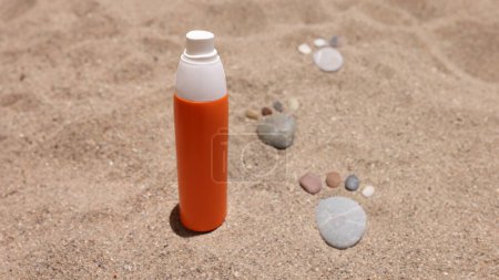 Orangefarbenes Glas mit Sonnencreme steht auf Sand in der Nähe von Steinabdrücken in Großaufnahme. Sonnenschutzkonzept für Kinder
