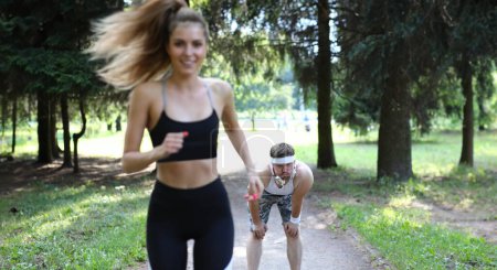 Mann und Frau auf Morgenlauf im Sommerpark. Ausdauertraining zielt darauf ab, das Herz zu stärken und die Ausdauer zu steigern. Motivation für Morgenlauf, um den Körper zu straffen. Positive Emotionen aus dem Sport.