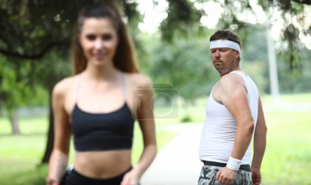 Photo for Man compares his figure with figure slender girl. Guy thinks about slim athletic body girl. After jogging people stay awake all day. Man feels pain in his back and neck. Guy heart rate increases - Royalty Free Image