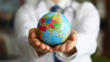 Männliche Arzthand hält Erde mit Virussymbol in Nahaufnahme. Covid 19 Online-Tracking-Konzept