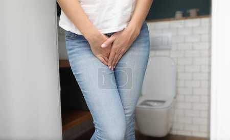 Foto de Manos femeninas entre las piernas en jeans de cerca. Diagnóstico y tratamiento del concepto de enfermedades de transmisión sexual. - Imagen libre de derechos