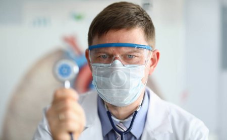 Male doctor hold in hand stethoscope with coronavirus symbol portrait. Coronavirus treatment antivirus concept.