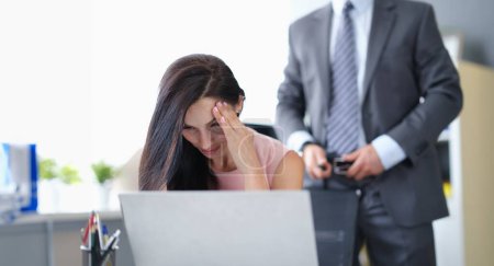 Femme effrayée s'assoit à l'ordinateur en arrière-plan homme d'affaires détache sa ceinture. Concept de stratégie de harcèlement