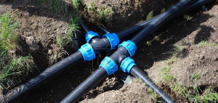 Téléchargez les photos : Connecting HDPE plastic water pipes in garden. Irrigation system and plastic pipes in ground - en image libre de droit