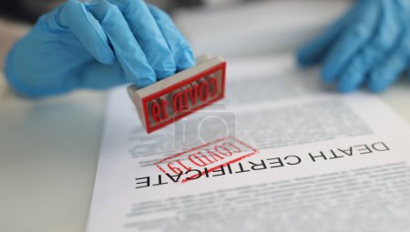 Téléchargez les photos : Doctor puts stamp on covid-19 death certificate. Pandemic mortality and coronovirus infection - en image libre de droit