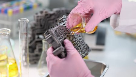 Wissenschaftler aus der Chemiekolben gießt Öl auf Getriebeventil Körper. Schmierstoffe für Autoteile