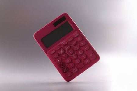 Pink calculator with numbers on gray background. Financial income growth and payment of taxes concept