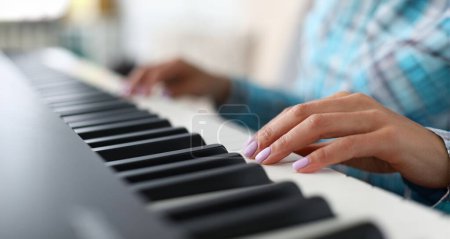 Close-up of female hands playing synthesizer in music workshop. Professional cute pianist creating new musical composition. Art concept. Blurred background