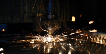 Téléchargez les photos : Sparks voler tête de machine pour le traitement des métaux laser métal sur fond d'usine métallurgique. Fabrication de pièces finies pour le concept de production automobile - en image libre de droit