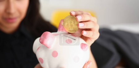 young beautiful brunette woman hold piggybank in arms put money into moneybox