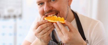 Photo for Man Chef Eating Juice Orange Kitchen Portrait. Blogger Person Bite Slice of Citrus Fruit on White Background. Healthy Lifestyle Concept. Cook Holding Fresh Food in Hands Looking at Camera Shot - Royalty Free Image