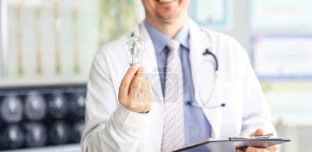 Photo for Male doctor hand holding lightbulb as bright idea invention symbol closeup - Royalty Free Image