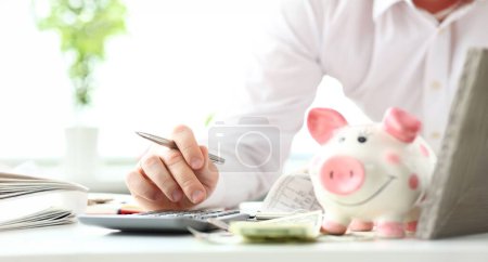 Photo for Hand of businessman counting something on calculator device holding financial bills in hand closeup - Royalty Free Image