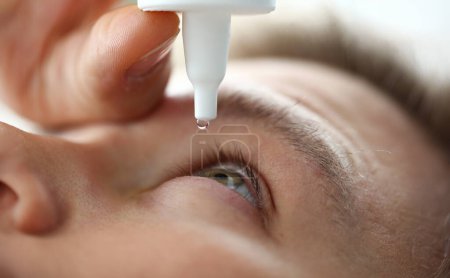 Photo for Male hand putting liquid drops in his eye solving vision problem closeup - Royalty Free Image