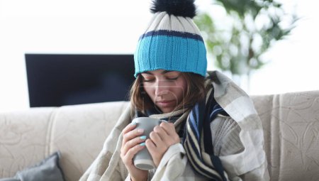 Photo for Portrait of smart lady sitting in living room and wearing warm clothes trying to cure sickness with traditional methods from severe illness. Hard virus concept - Royalty Free Image