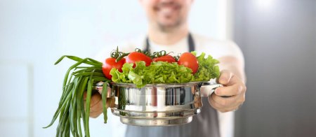 Photo for Chef Blogger Holding Vegetable Variety Saucepan. Man Cooking from Tomato, Salad and Spring Onion. Fresh and Organic Ingredients. Pan with Vegan Food. Vegetarian Lifestyle. Partial View Photography - Royalty Free Image