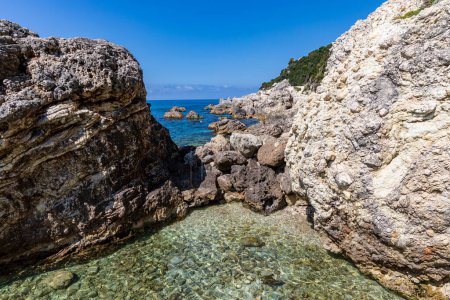 Photo for A beautiful landscape of the coast of the island of Corfu in the Ionian Sea of the Mediterranean in Greece. Pure blue clear water washes over the shores of the Greek island. - Royalty Free Image