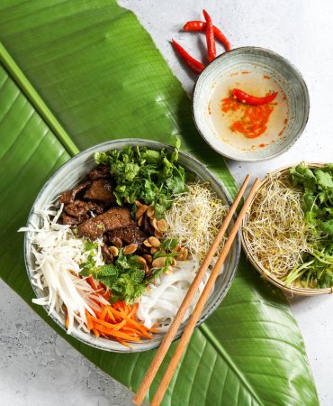 Téléchargez les photos : Bol de salade vietnamienne traditionnelle - Bun Bo Nam Bo, avec bœuf, nouilles de riz, herbes fraîches, légumes marinés et sauce de poisson - en image libre de droit
