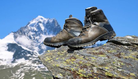 Foto de Zapatillas de senderismo en la roca, al fondo Monte Aiguille Verte en la Reserva Natural de Aiguilles Rouges, Alpes de Graia, Francia. - Imagen libre de derechos