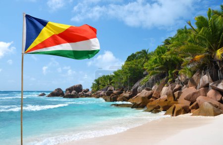 Foto de Anse Cocos beach with flag of  Seychelles in the La Digue Island, Indian Ocean.Tropical landscape with sunny sky. Exotic travel destination. - Imagen libre de derechos
