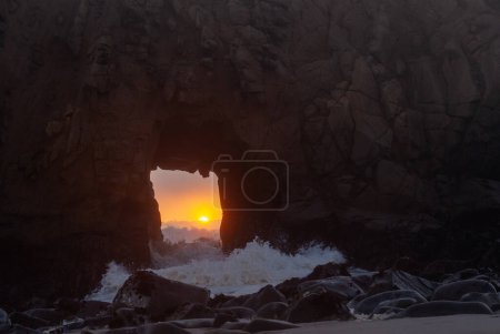Photo for The setting sun is peaking through the keyhole arch at Pfeiffer Beach, near Big Sur. - Royalty Free Image