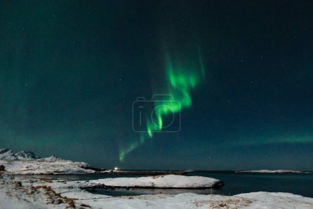 Photo for Bright Green Colours of the Northern Light, Aurora Borealis illuminate the Night Sky over the beach at Mjelle, in Arctic Norway. - Royalty Free Image