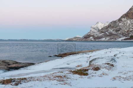 Photo for Landscape shot highlighting the rugged mountains and snow-covered beaches of arctic norway during a brief golden hour during the long winters. - Royalty Free Image