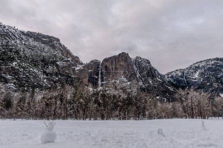 Téléchargez les photos : Vue d'ensemble de trois bonhomme de neige construit dans la vallée de Yosemite, avec les célèbres chutes en arrière-plan. - en image libre de droit