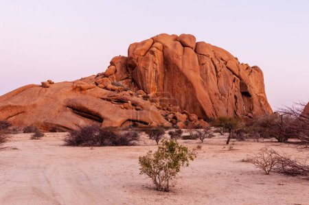 Foto de Formaciones rocosas audaces que brillan de color naranja brillante en los últimos rayos del sol poniente. Spitzkoppe, Namibia. - Imagen libre de derechos
