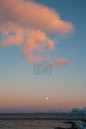 Photo for Landscape shot highlighting a near full moon over the rugged mountains of arctic Norway, near Bodo, during golden hour. - Royalty Free Image