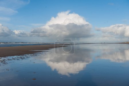 Photo for Clouds reflecting in a residu of water on the Beach near Egmond aan Zeen in North Holland, the Netherlands. - Royalty Free Image