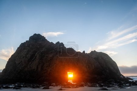 Téléchargez les photos : Vue grand angle de l'arche du trou de serrure à la plage de Pfeiffer, Californie, le soleil couchant jetant un coup d'oeil à travers le trou central. Coucher de soleil sur une soirée d'hiver en Californie. - en image libre de droit