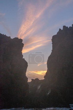 Photo for Water is flowing through a narrow opening in the rocks at Pfeiffer beach, during sunset. - Royalty Free Image