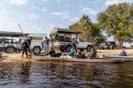 Photo for Okavango Delta, Botswana - August 2, 2022. A group of travelers prepare for a boat trip in a mokoro, along the delta. This type of travel is traditional among the locals of the delta. - Royalty Free Image