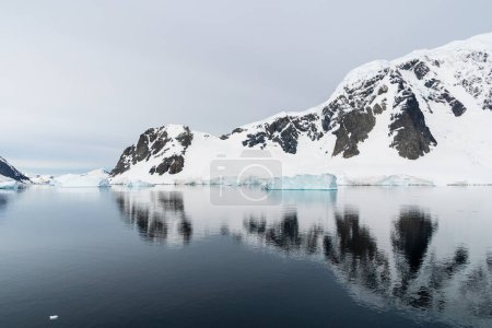 Foto de Los icebergs y los glaciares alinean la costa de la península antártica, y sus muchas islas. Un mar muy tranquilo refleja la luz de la madrugada en el estrecho de Gerlache. - Imagen libre de derechos