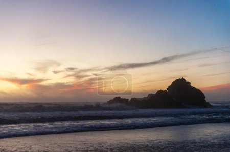 Téléchargez les photos : Rochers dans le surf de la plage de Pfeiffer, autour du coucher du soleil. Les nuages orange jaune profond colorent le ciel. - en image libre de droit