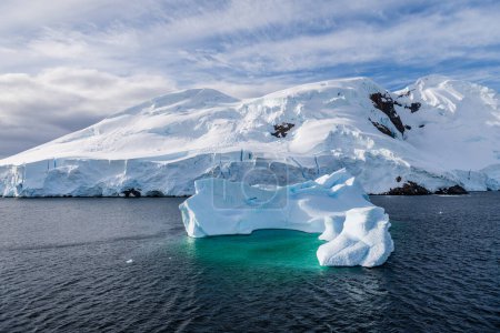 Foto de Un tranquilo paisaje antártico, cerca del paso de Graham a lo largo de la bahía de Charlotte, destacando reflejos crudos, montañas escarpadas e impresionantes icebergs. - Imagen libre de derechos